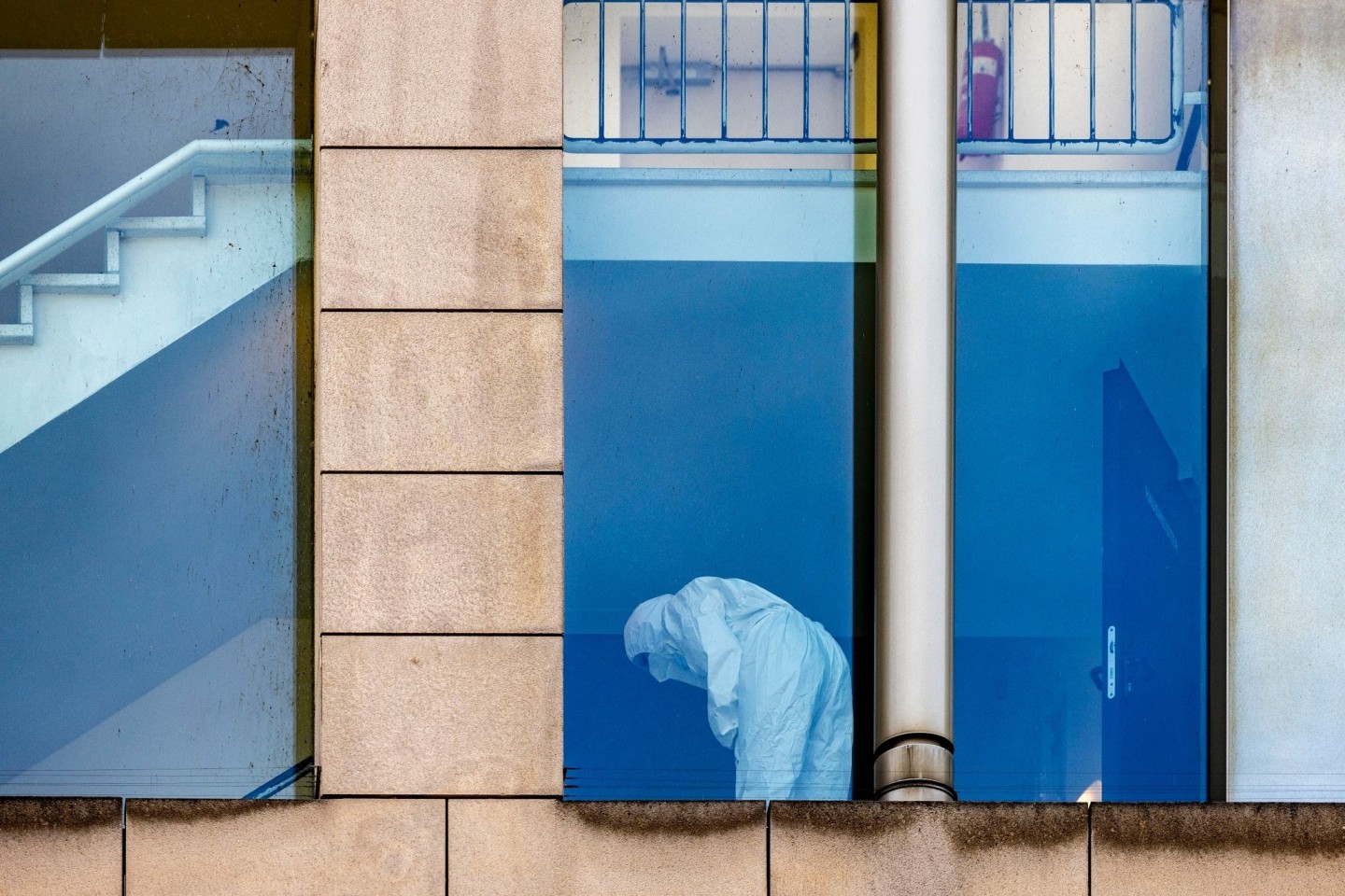 Eine Beamtin der Polizei untersucht in Schutzkleidung das Treppenhaus.