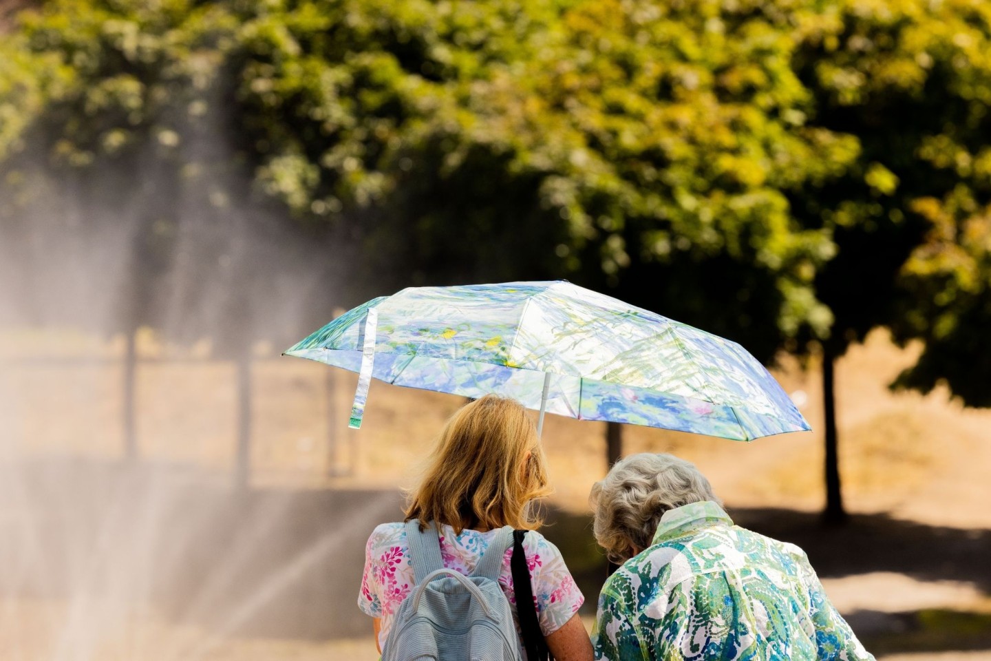 Zwei Frauen am Kölner Rheinufer mit Sonnenschirm.