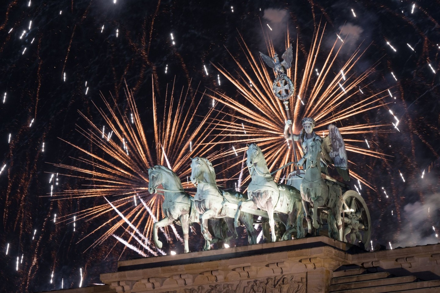 Das Feuerwerk zum Jahreswechsel steigt hinter dem Brandenburger Tor auf.