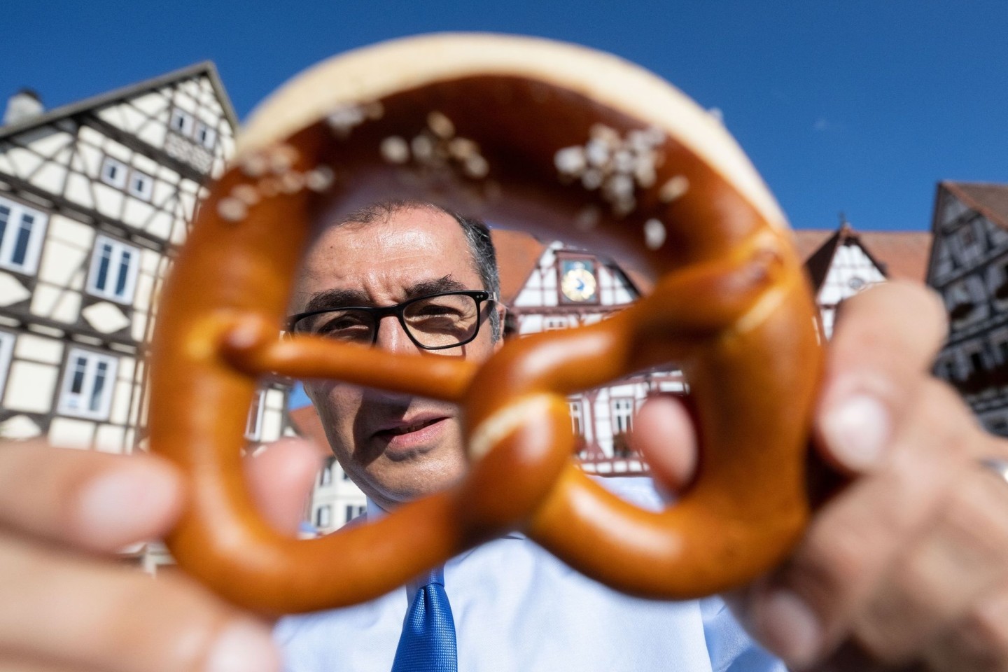 Cem Özdemir (Bündnis 90/Die Grünen) lugt hinter einer Brezel hervor.