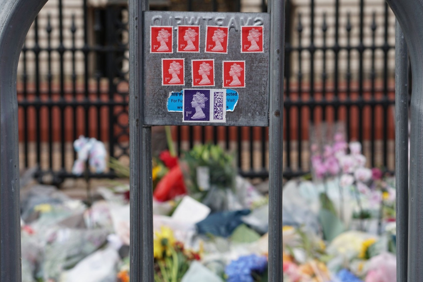 Briefmarken mit dem Konterfei der Queen kleben an einem Zaun am Buckingham-Palast.