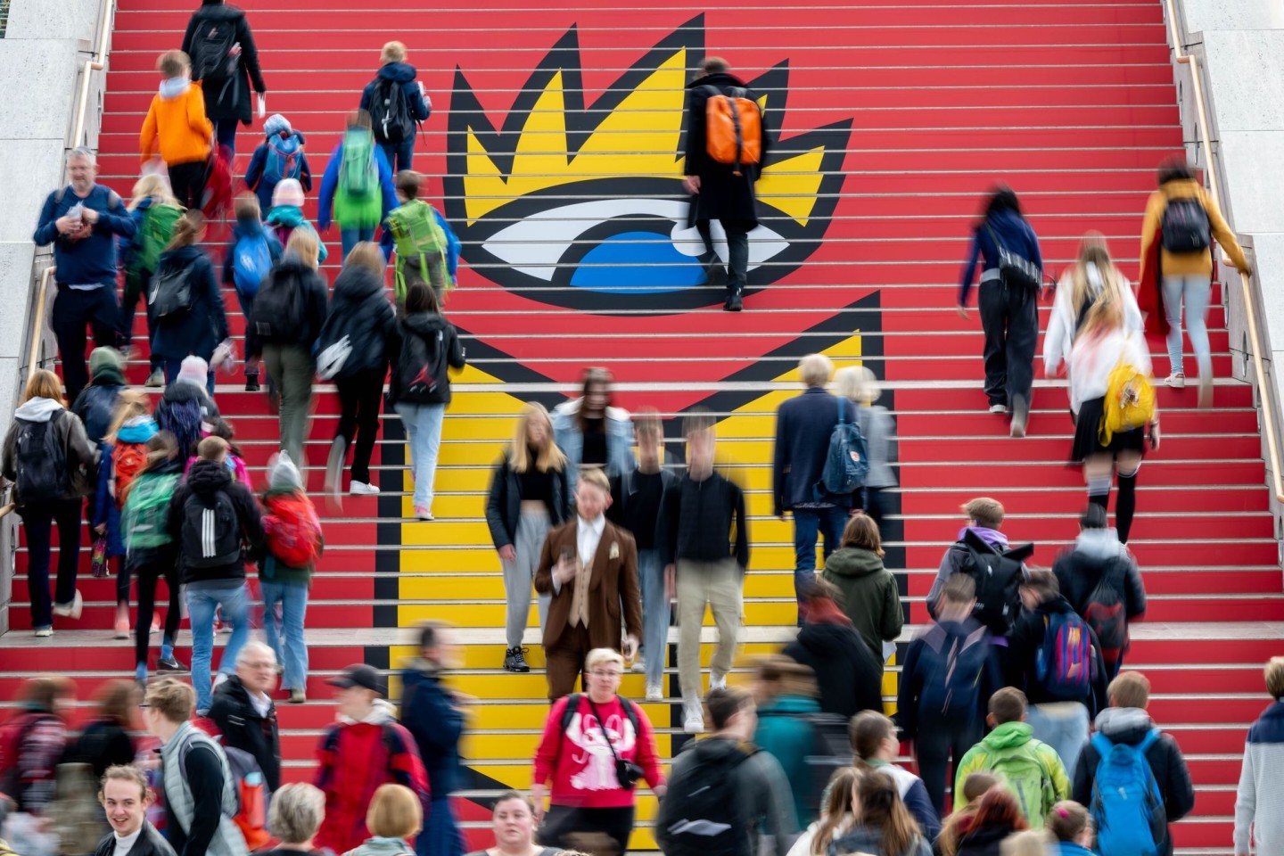 Viel Andrang: Besucherinnen und Besucher der Leipziger Buchmesse gehen zur Eröffnung über eine Treppe mit dem Logo der Buchmesse.