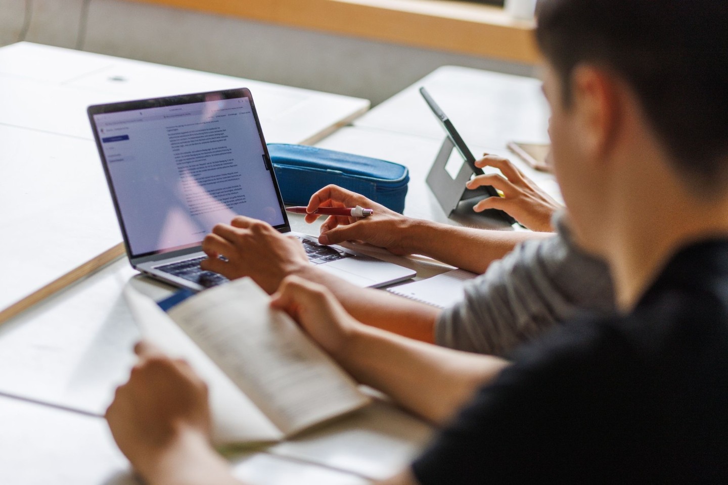 Schüler eines Gymnasiums sitzen vor einem Computer und benutzen ein KI-Tool.