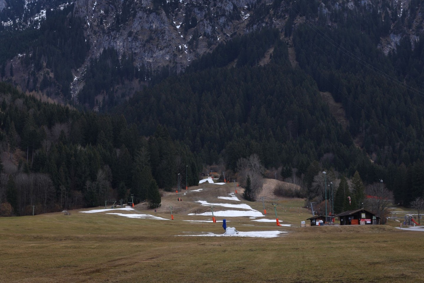 Reste von Kunstschnee auf einer Skipiste in grüner Landschaft.