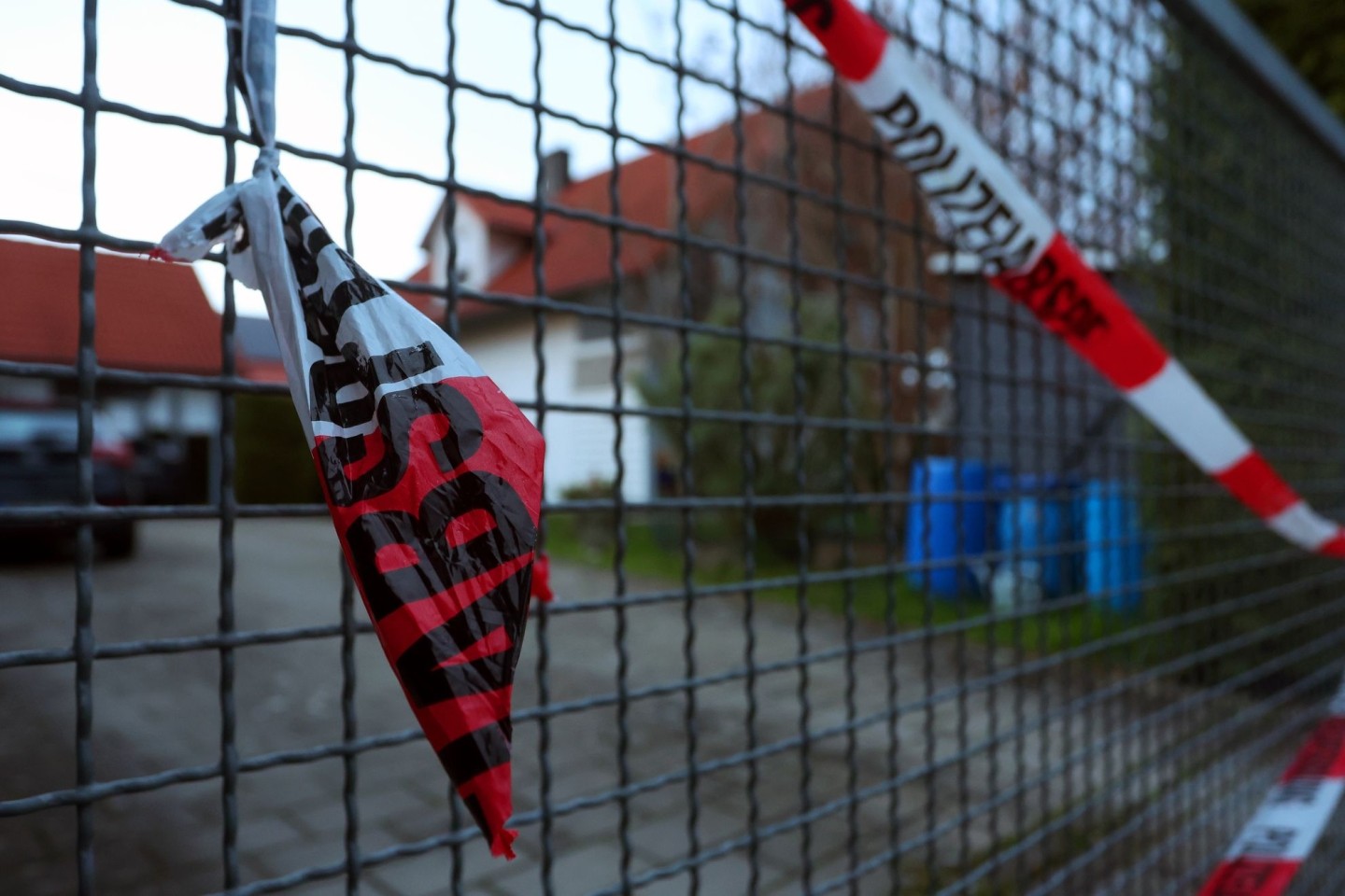 Ein Absperrband der Polizei hängt am Hoftor des Einfamilienhauses, in dem die Leichen eines Ehepaars entdeckt wurden.