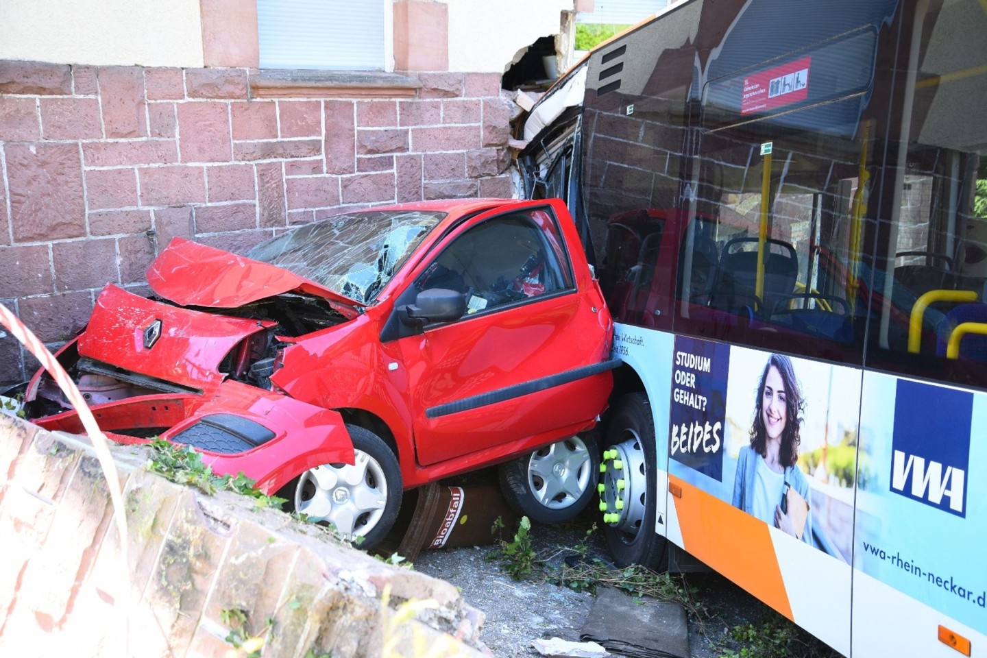 Ein zerstörtes Auto und der Linienbus, der in ein Haus gekracht ist.