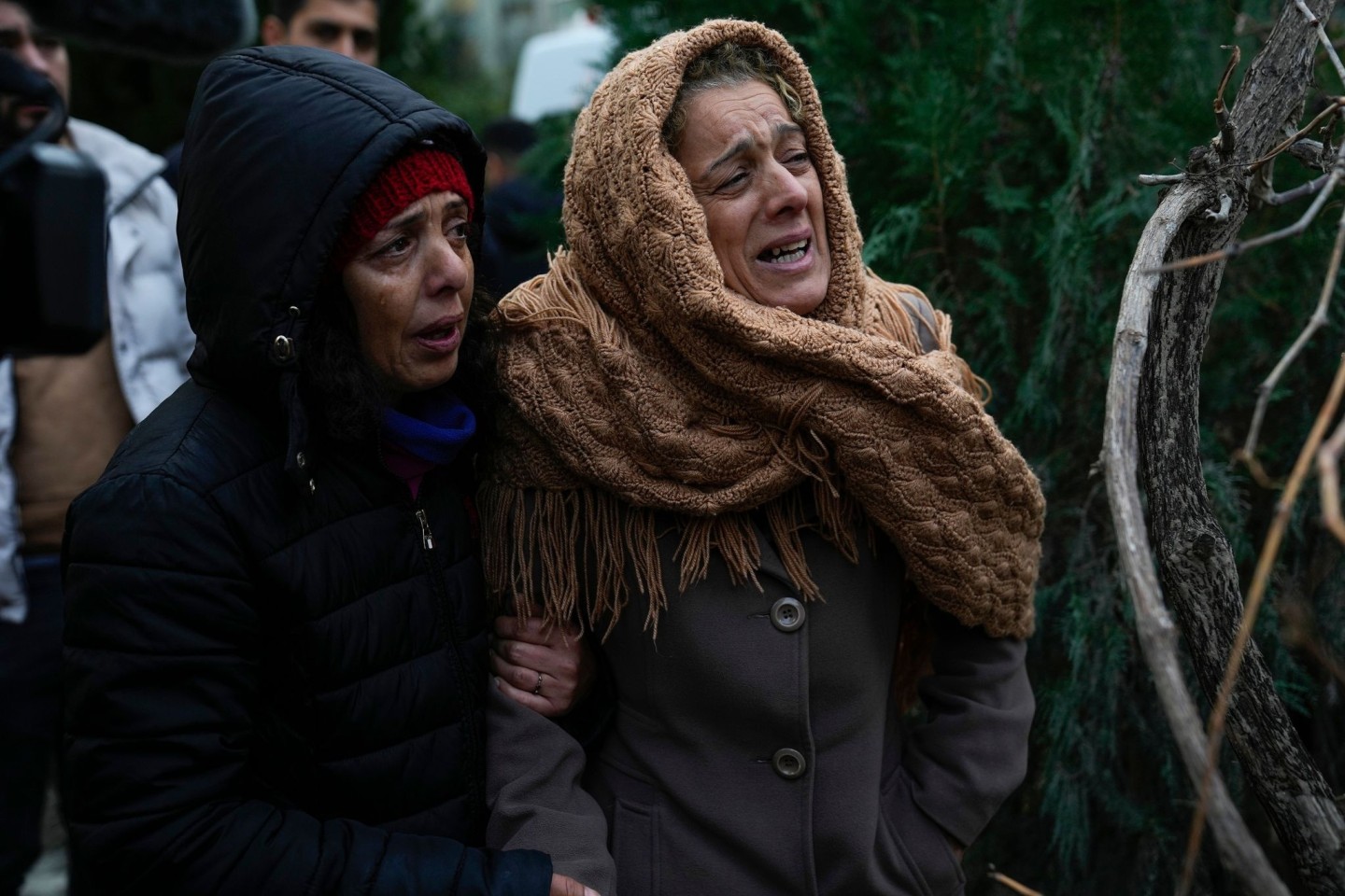 Frauen weinen, während sie zusehen, wie die Rettungskräfte in den Trümmern eines zerstörten Gebäudes in Adana nach Menschen suchen.