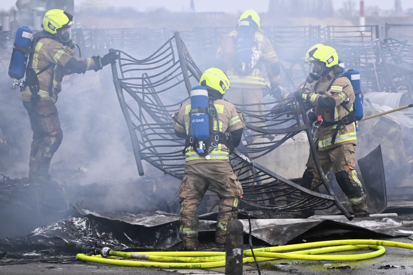 Feuerwehrmänner löschen die letzten Brandstellen in der Flüchtlingsunterkunft am ehemaligen Flughafen Tegel.