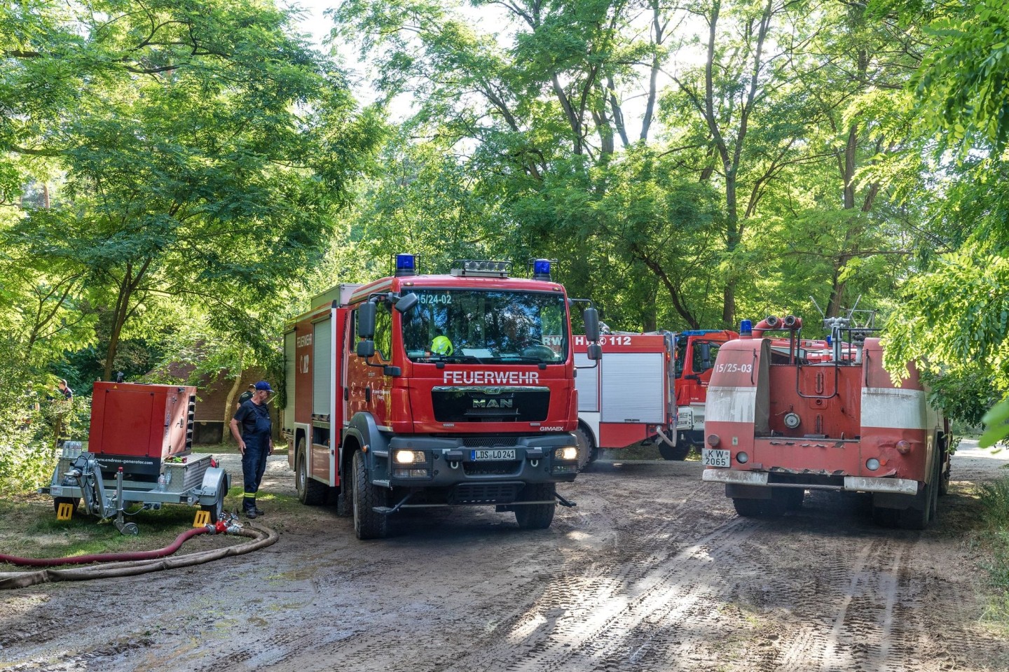 Ein Fahrzeug der Feuerwehr fährt in der Nähe des Einsatzortes durch den Wald.