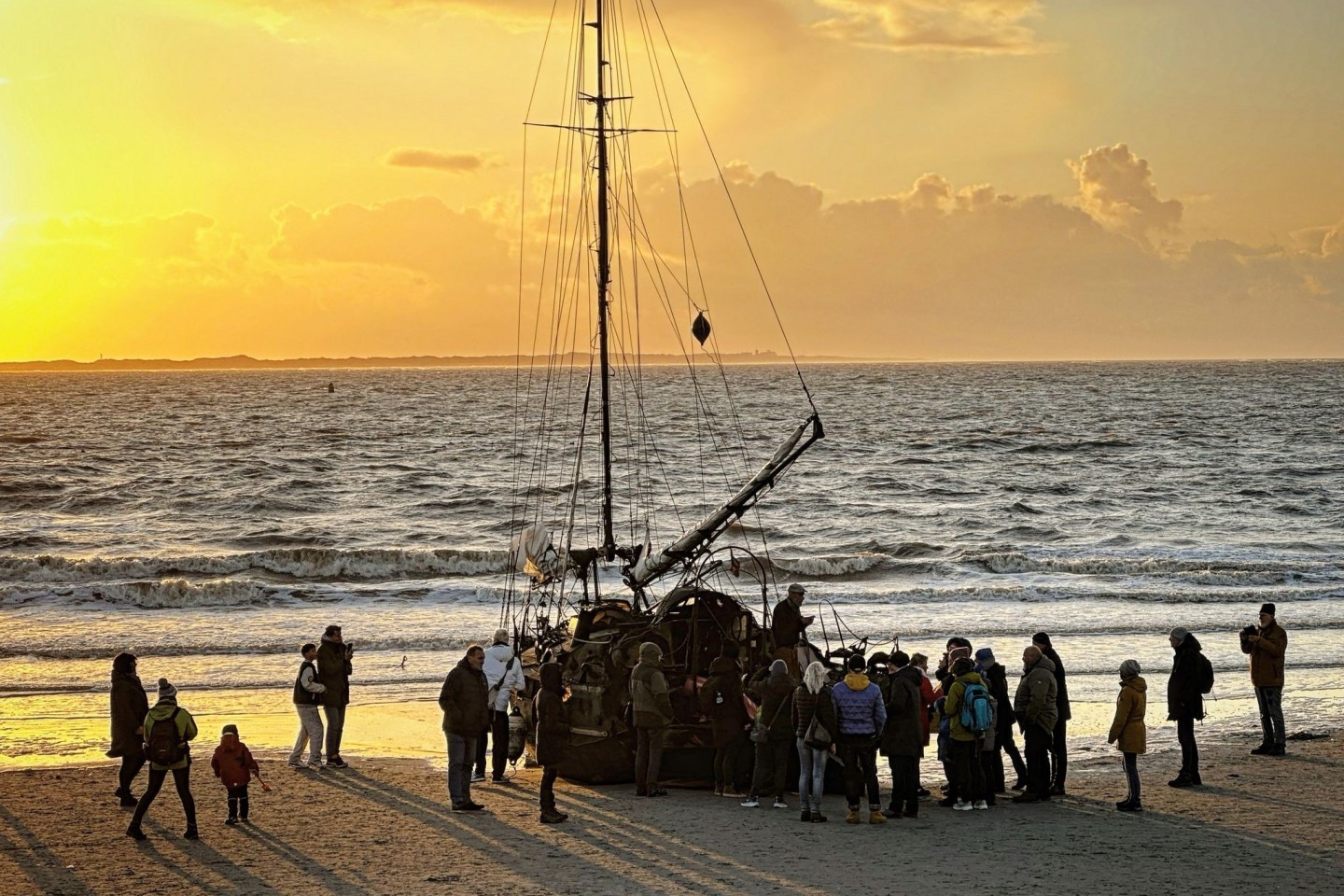 Ein am Weststrand der Insel Norderney gestrandetes Segelschiff mit Schaulustigen.