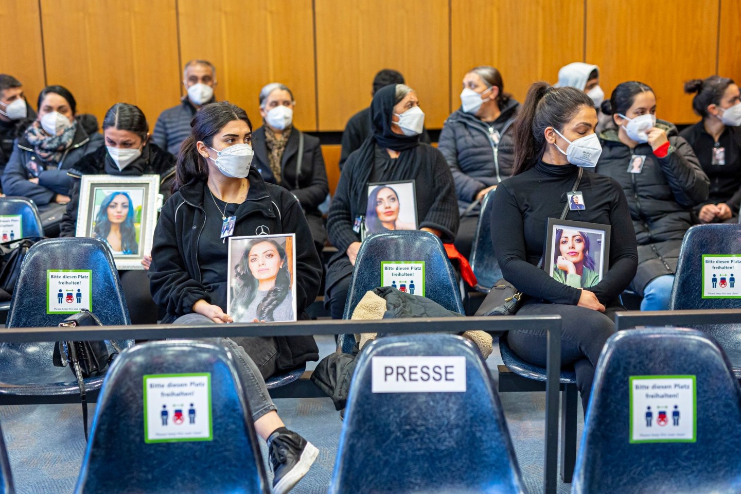 Angehörige der Getöteten sitzen mit Porträtfotos der Frau beim Prozessauftakt in einem Saal vom Landgericht Hildesheim. Auch am zweiten Verhandlungstag wurden viele Bilder mitgebracht.