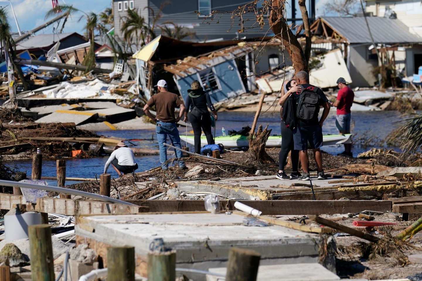 Menschen betrachten von einer zerstörten Brücke in Matlacha im US-Bundesstaat Florida aus die Schäden.