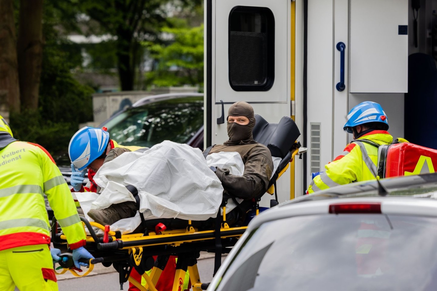 Ein verletzter Polizeibeamter wird vor einem Hochhaus in einen Krankenwagen gebracht.