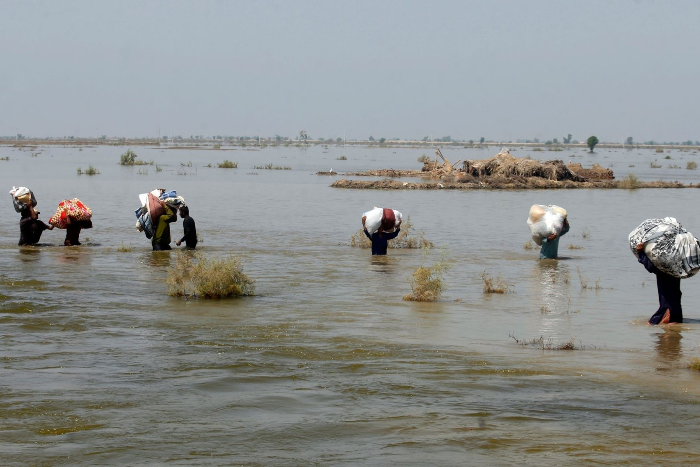 Opfer der schweren Überschwemmungen durch Monsunregen tragen in der Provinz Sindh Hilfsgüter durch das Hochwasser.