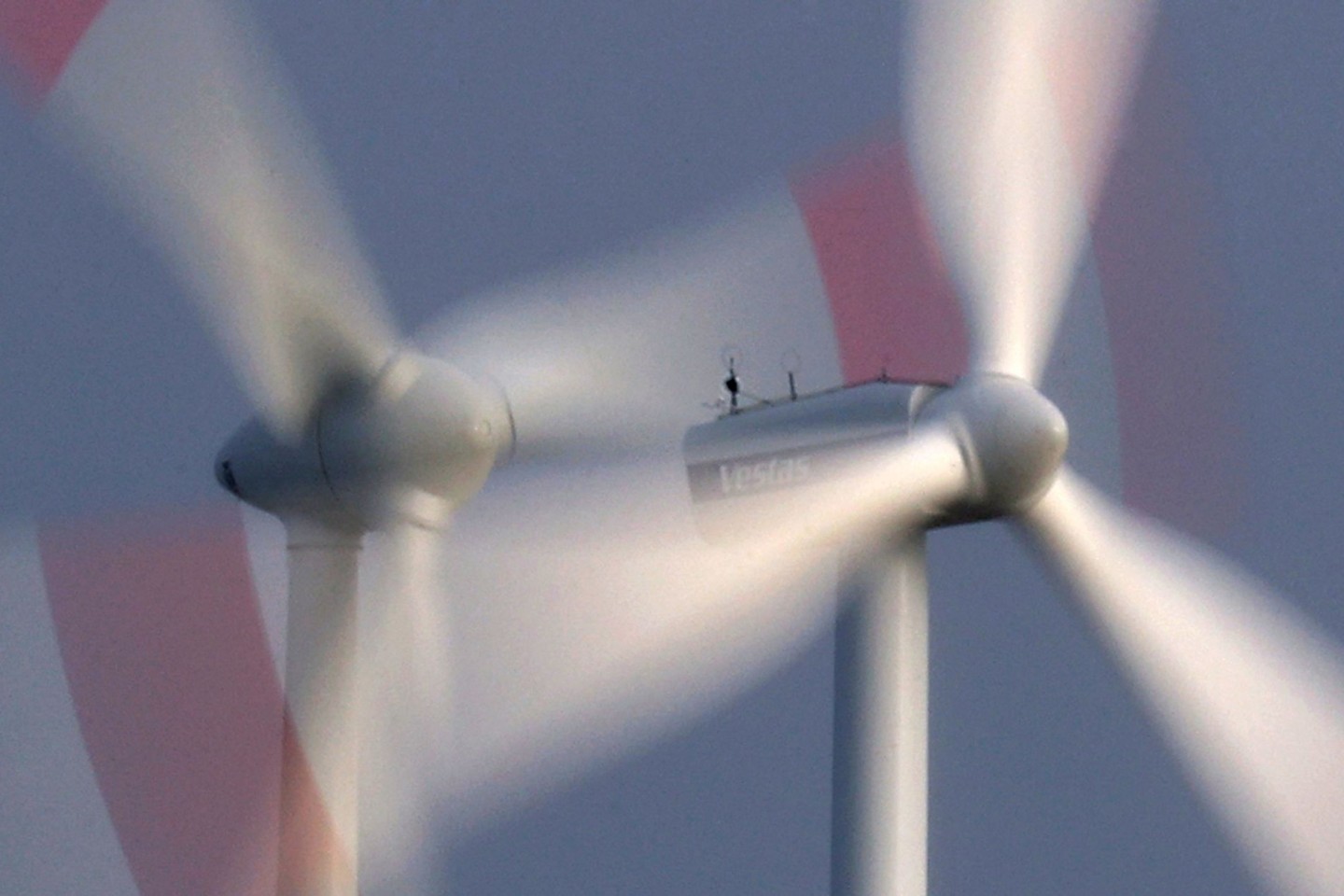 Zwei Windräder drehen sich bei heftigem Wind vor wolkenüberzogenem Himmel.