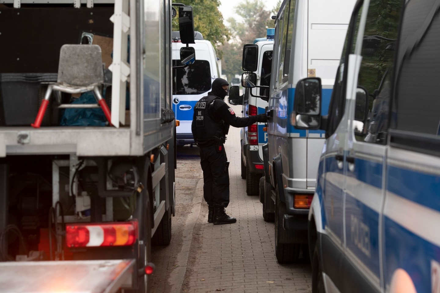 Ein Polizeibeamter steht zwischen Einsatzfahrzeugen am Vereinsheim der Rockergruppe 