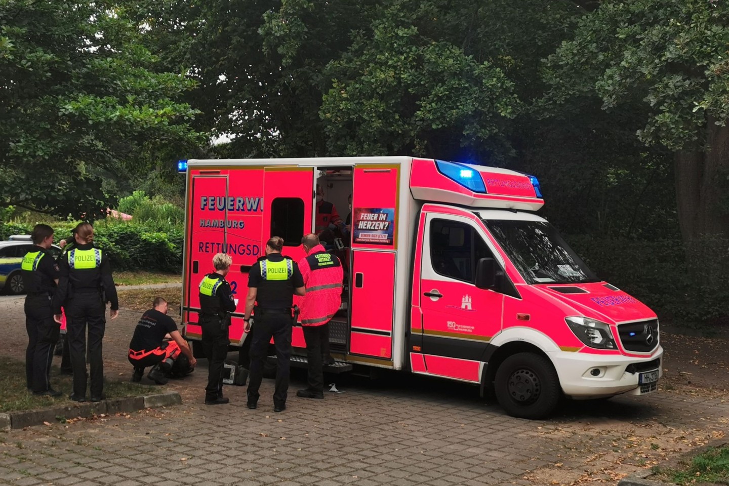 Rettungskräfte stehen an ihrem Einsatzwagen. Sie brachten drei Jugendliche aus einem Park ins Krankenhaus.