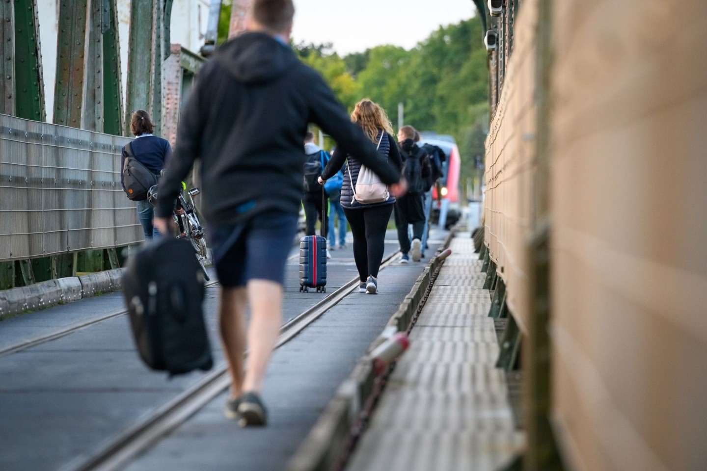 Fahrgäste laufen mit Koffern und anderem Gepäck über die Schleibrücke bei Lindaunis.