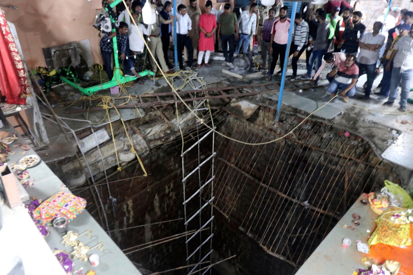 Menschen stehen an einem alten Brunnenbauwerk, über dem ein Tempel gebaut worden war, dessen Boden eingestürzt ist.