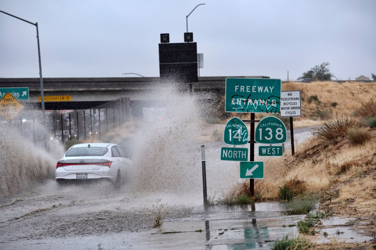 Ein Fahrzeug fährt durch eine überflutete Autobahnauffahrt nahe der kalifornischen Stadt Palmdale.