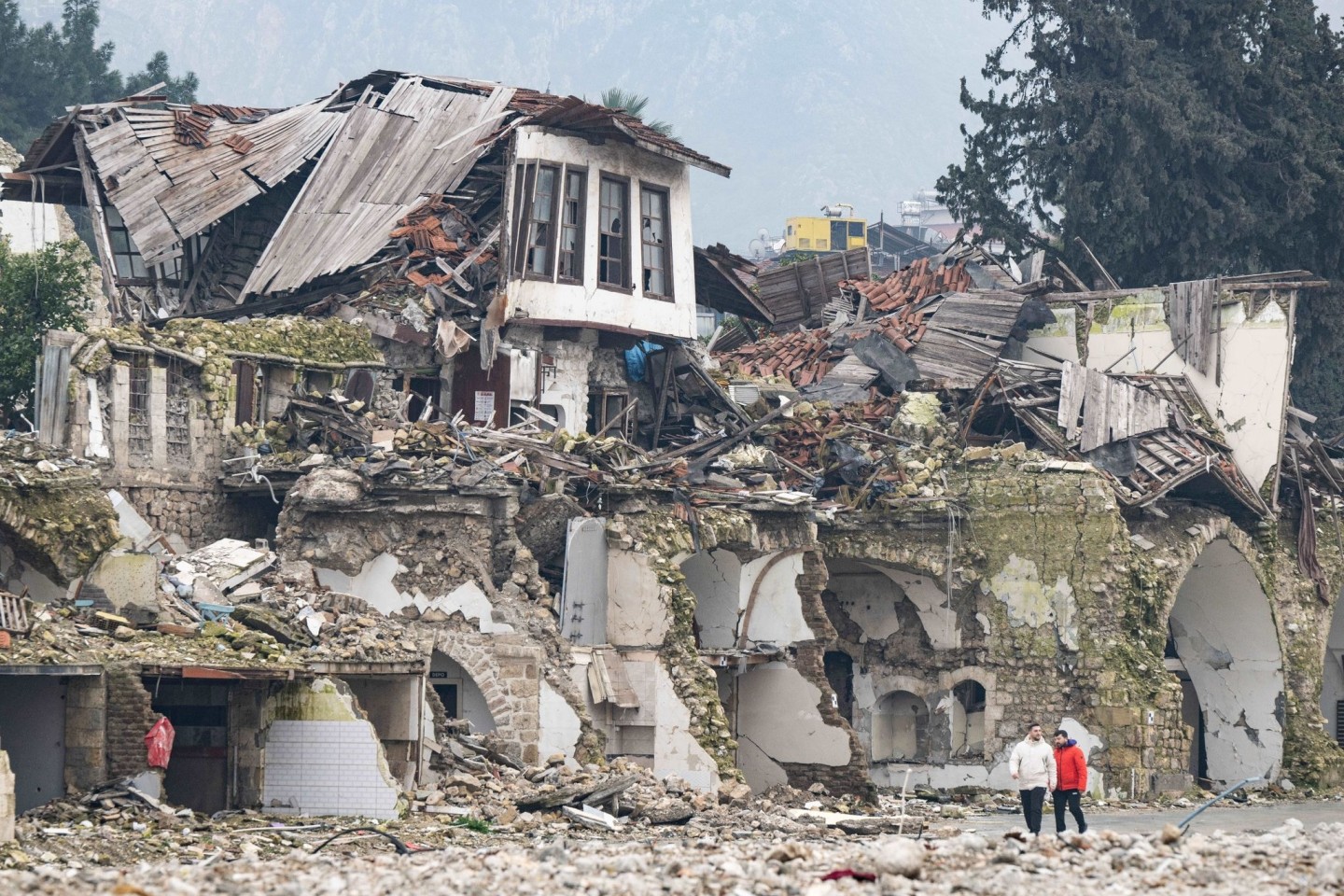 Zwei Männer gehen an einer völlig zerstörten Häuserzeile in Antakya vorbei. Im Zentrum der Stadt waren bei dem Beben vor einem Jahr unzählige Häuser zerstört oder beschädigt worden.