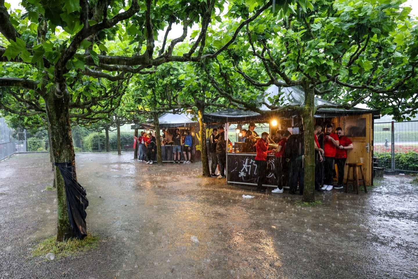 Zumindest ein bisschen Schutz: Fussballfans in Dortmund haben sich beim strömenden Regen an Imbissbuden untergestellt.