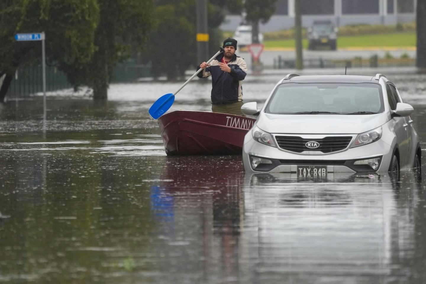 Ein Mann paddelt mit seinem Boot auf einer überfluteten Straße am Stadtrand von Sydney.