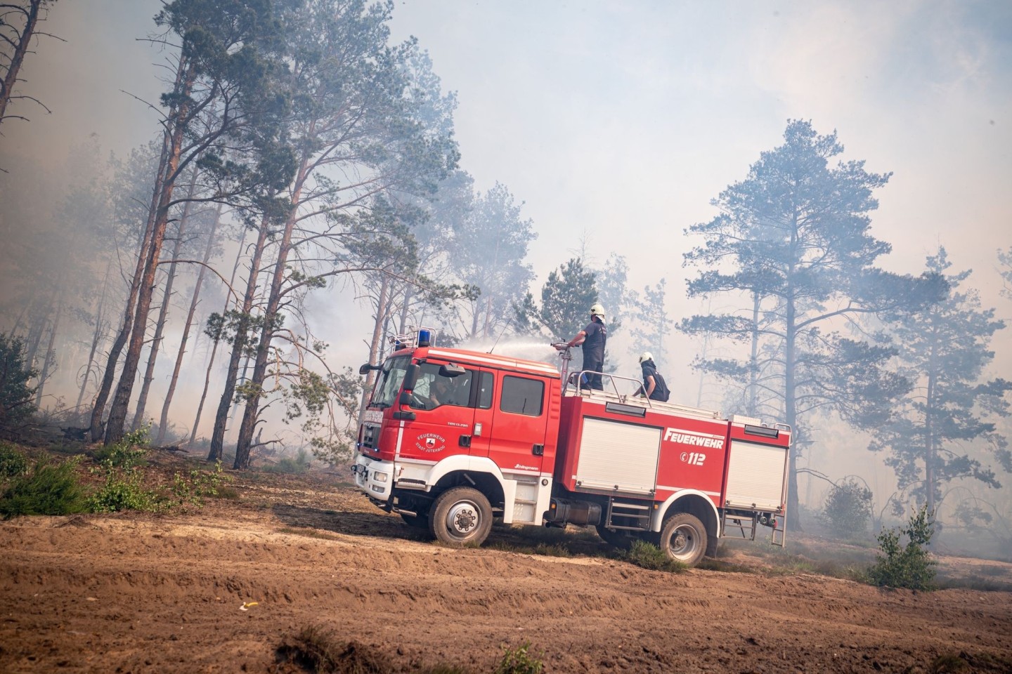 Einsatzkräfte der Feuerwehr bekämpfen in einem Waldstück nahe Jüterbog das Feuer.