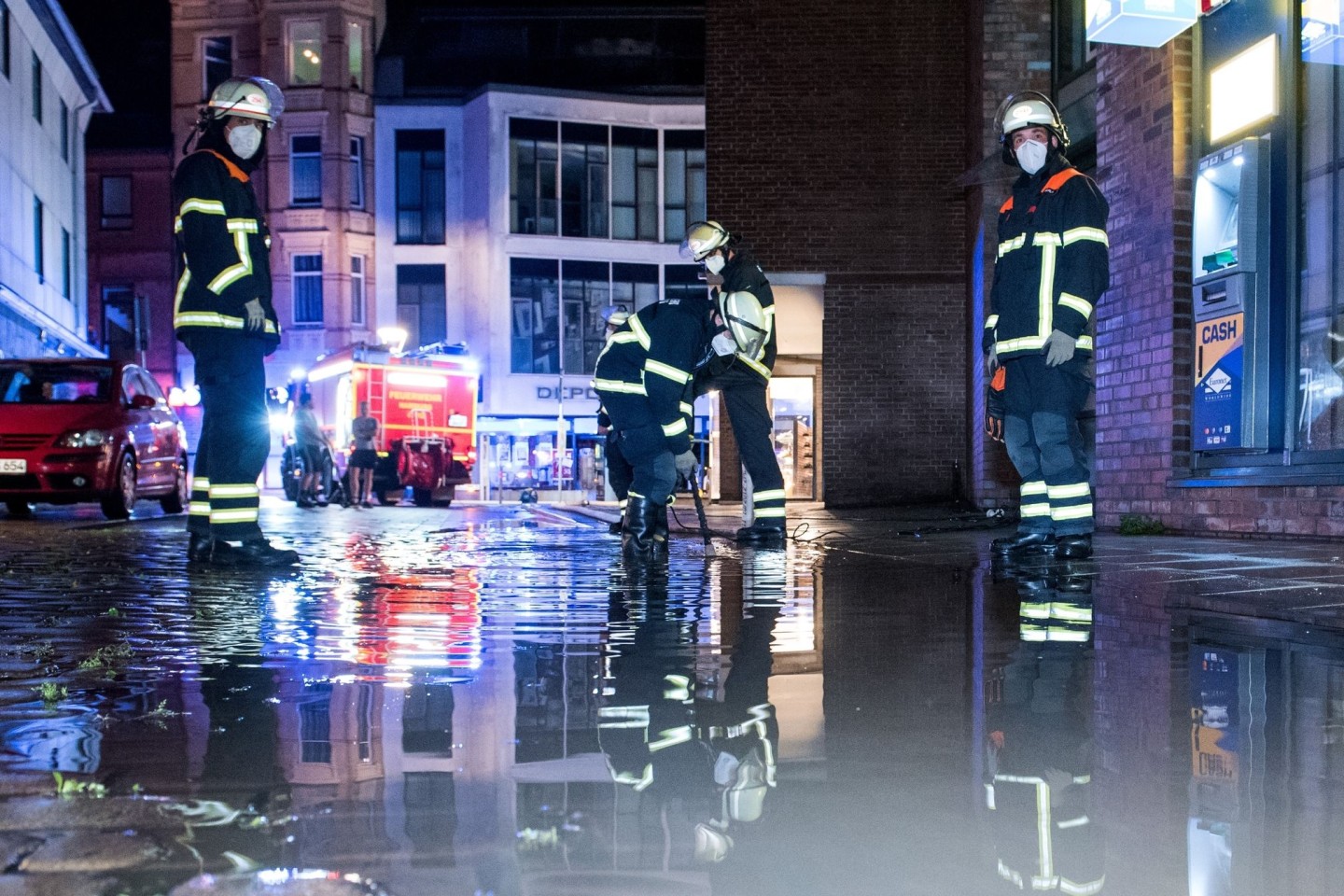 Feuerwehrleute pumpen in Hamburg Wasser von einer überfluteten Straße ab.