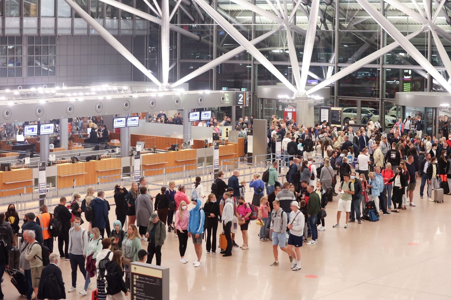 Reisende stehen am Morgen in einer Schlange die zur Sicherheitskontrolle am Hamburger Flughafen führt. In Hamburg haben die Ferien begonnen.