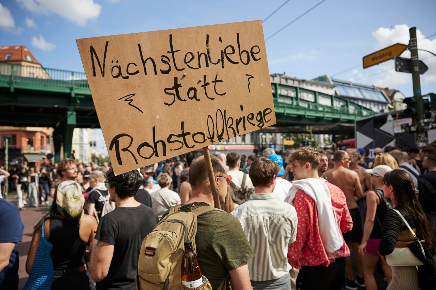 Ein Feiernder trägt ein Schild mit der Aufschrift «Nächstenliebe statt Rohstoffkriege» bei der Technoparade Zug der Liebe durch Berlin.